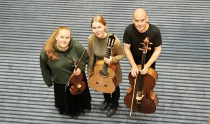 kolme klassisien musiikin muusikko vieretysten, soittimet käsissään