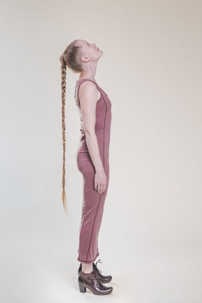 Anna Fält, nainen seisoo sivuittain ruskean taustan edessä